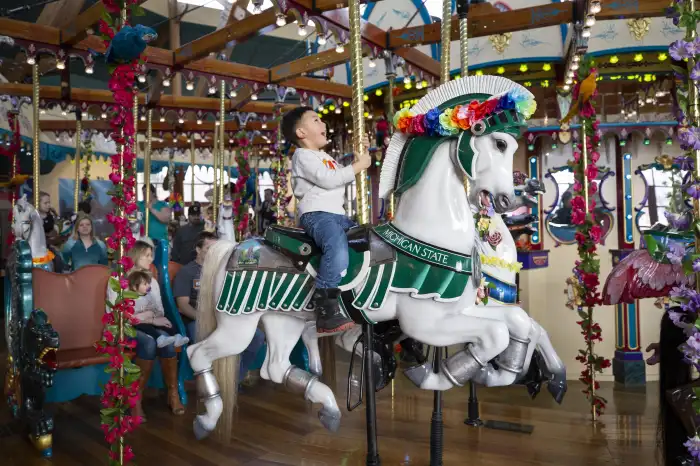 child riding carousel horse
